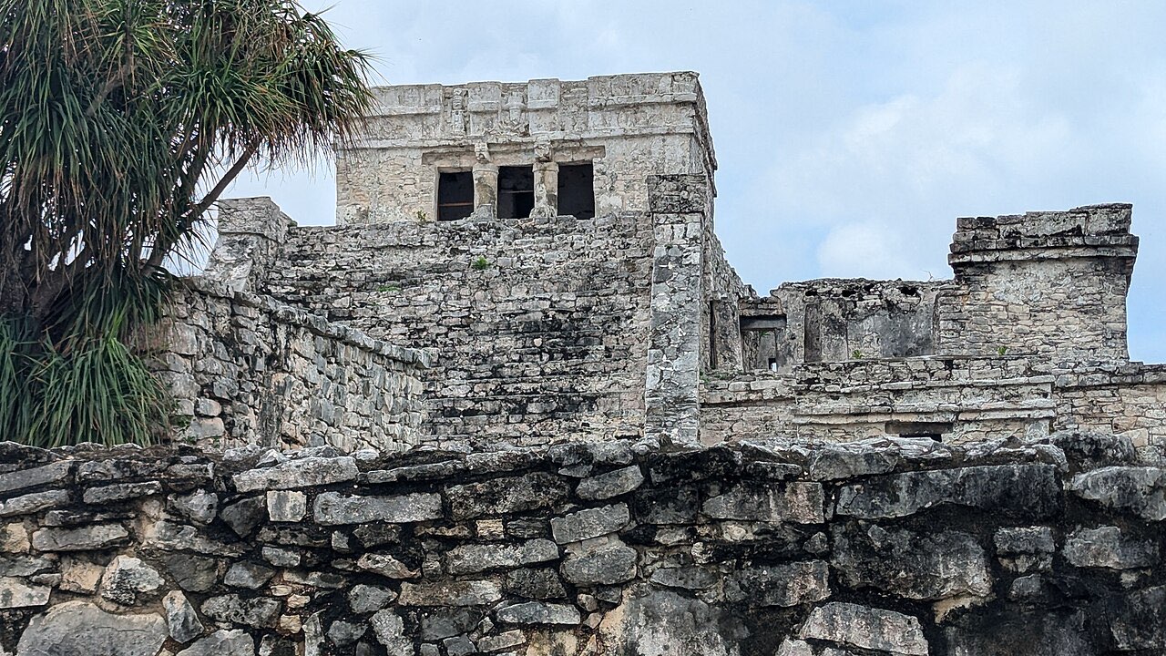 Front view of El Castillo, the main temple at Tulum, seen over a stone wall